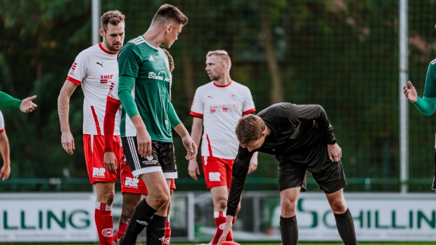 Auf dem Foto sieht mein einen Schiedsrichter, der bei einem Fußballspiel im Amateurbereich pfeift.