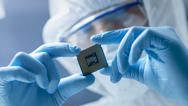 Person in Schutzanzug begutachtet Mikrochip
