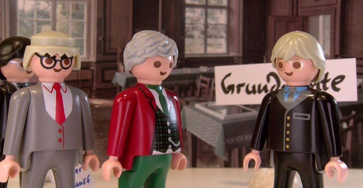 (c) Sommers Weltliteratur to go. Drei Playmobilfiguren stehen im Plenarsaal der neuen Dauerausstellung zum Verfassungskonvent auf Herrenchiemsee