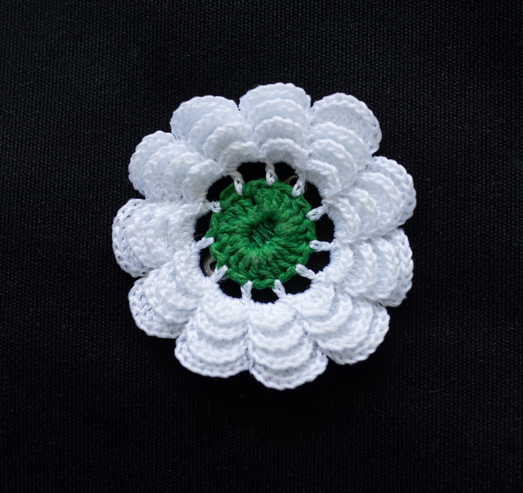 weiße Blume mit 11 Blütenblättern um grünen Kelch in gehäkelter Form - die Blume shte symbolisch für die Erinnerung an das Massaker von Srebrenica